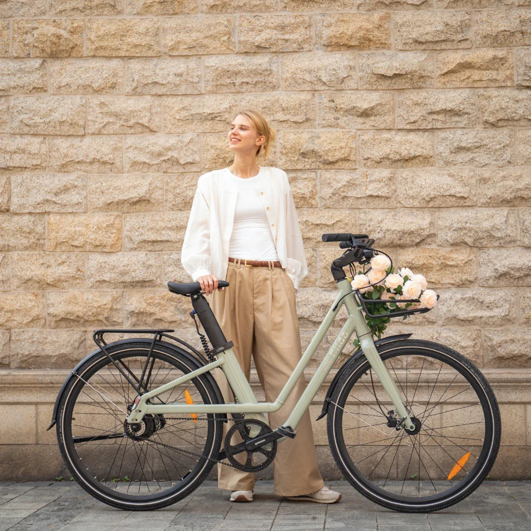 Žena pozira pored maslinastozelenog električnog bicikla Fiido City C700 s košarom cvijeća
