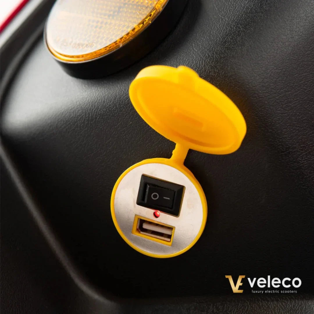 USB priključak s prekidačem na električnom skuteru Veleco Draco, krupni plan žutog poklopca