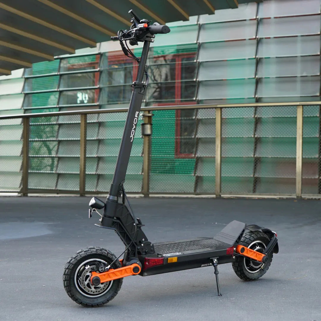 Crni električni romobil Joyor S-Pro s narančastim detaljima na ovjesu, pogled s bočne strane