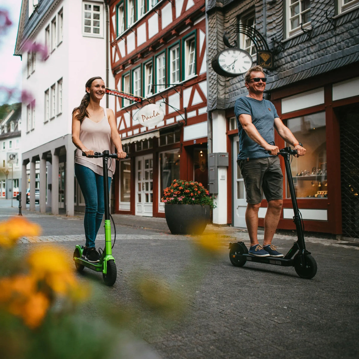 Par vozi električni romobil Streetbooster Vega u zelenoj i crnoj boji ulicom staroga grada