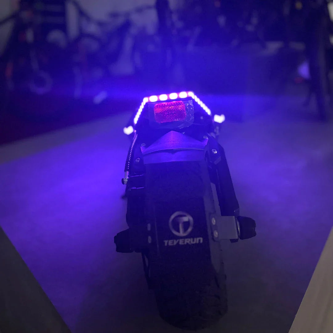 Stražnji pogled na električni romobil Teverun Fighter Mini Pro 2025 s upaljenim plavim LED svjetlima