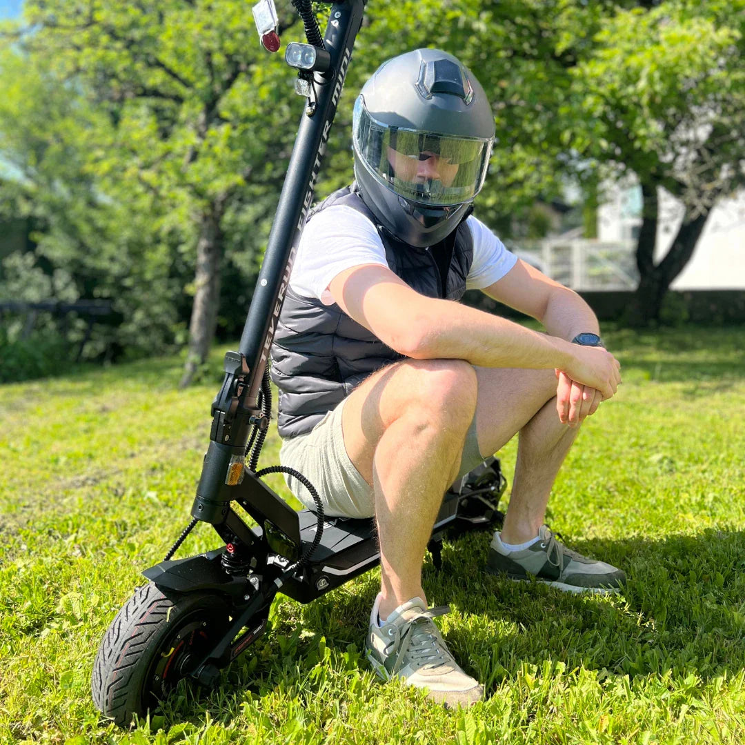 Vozač s kacigom sjedi na crnom električnom romobilu Teverun Fighter Mini Pro 2025 u prirodi