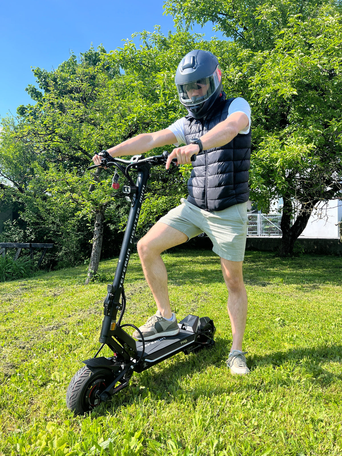 Muškarac s kacigom vozi crni električni romobil Teverun Fighter Mini Pro 2025 na otvorenom