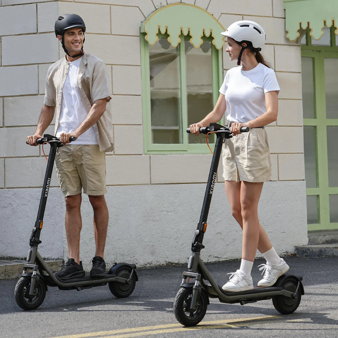 Muškarac i žena voze Xiaomi 6 Lite električne romobile na ulici ispred zgrade