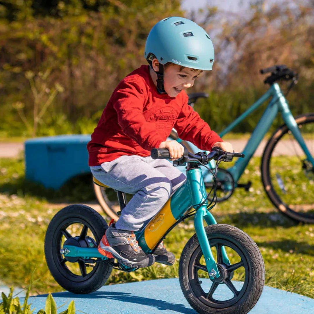 Dijete vozi plavo-žutu električnu guralicu Fiido Kidz u prirodi, pogled sprijeda