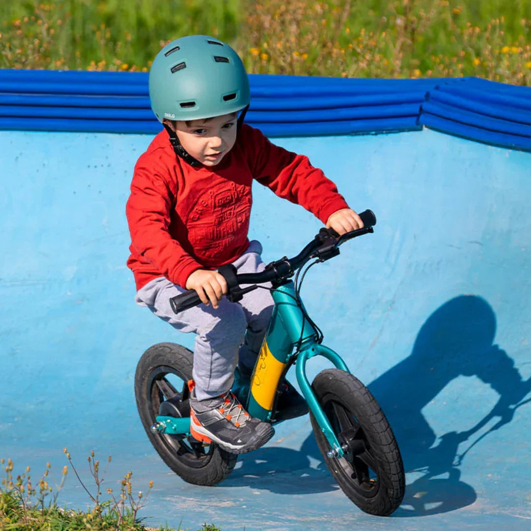 Dijete vozi električnu guralicu Fiido Kidz tirkizne boje u plavom skate parku