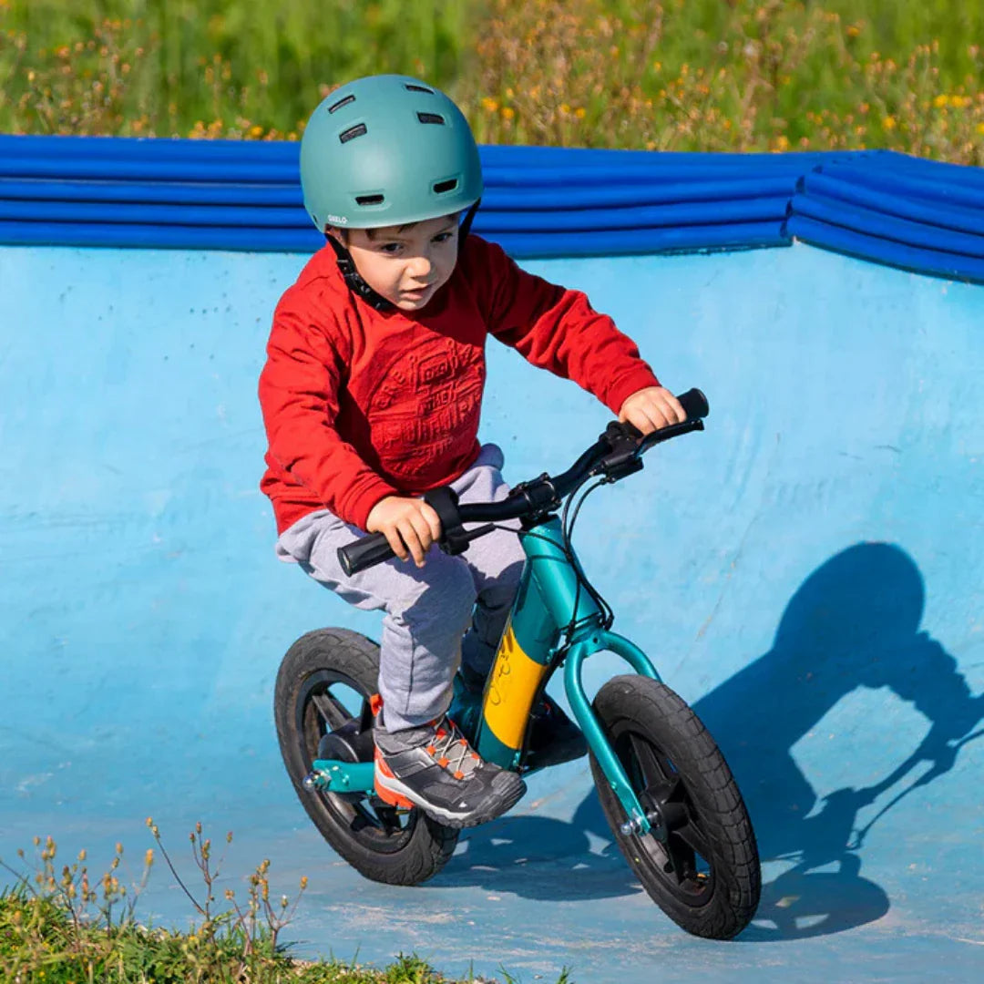 Dijete vozi plavo-žutu električnu guralicu Fiido Kidz u plavom skate parku