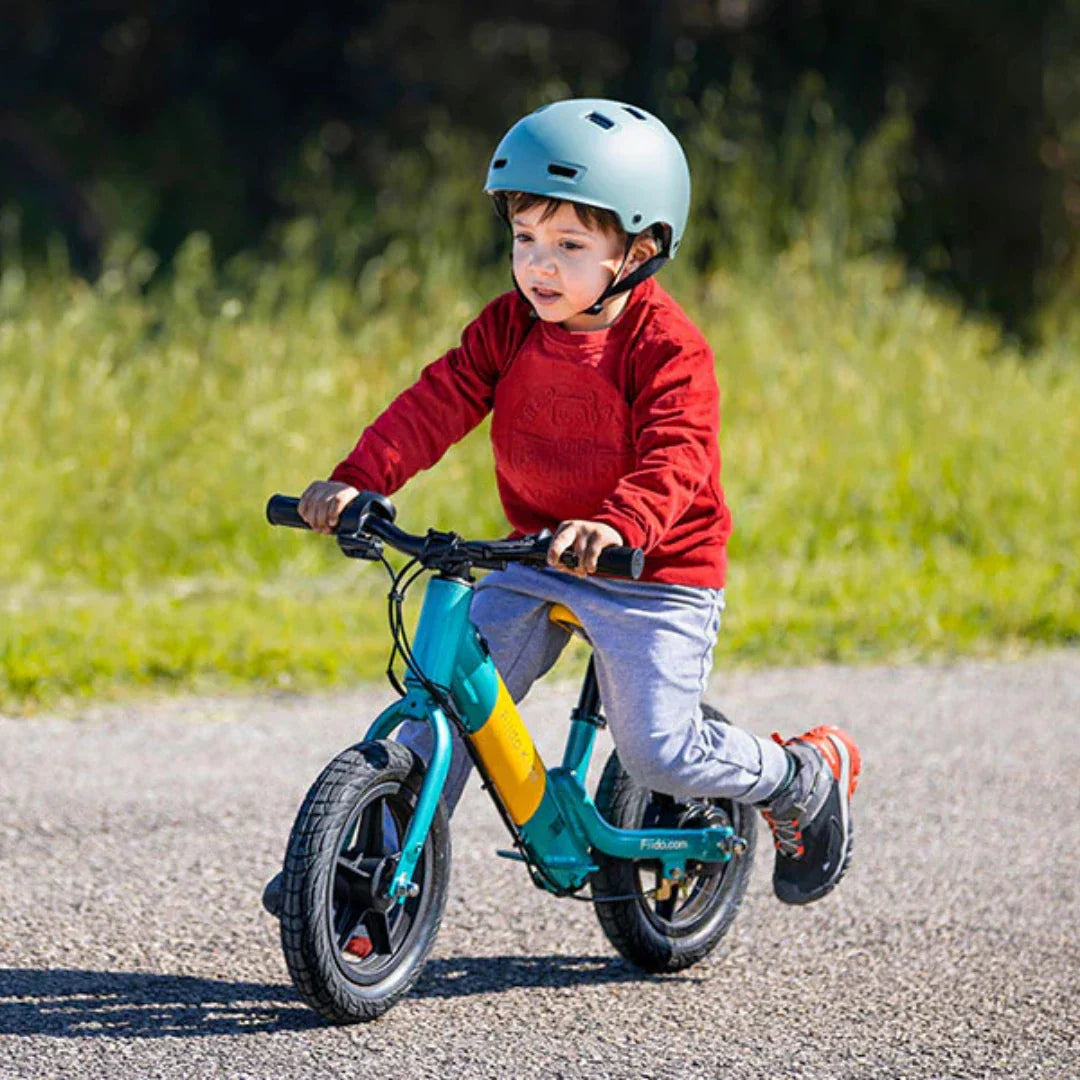 Dijete vozi plavo-žutu električnu guralicu Fiido Kidz na otvorenom