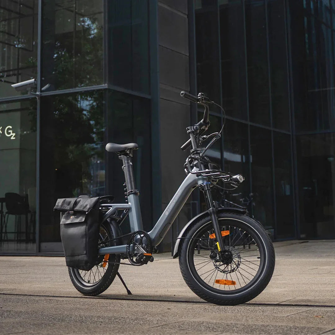 Sivi električni bicikl ADO Air One PRO s bisagama, bočni pogled ispred moderne zgrade