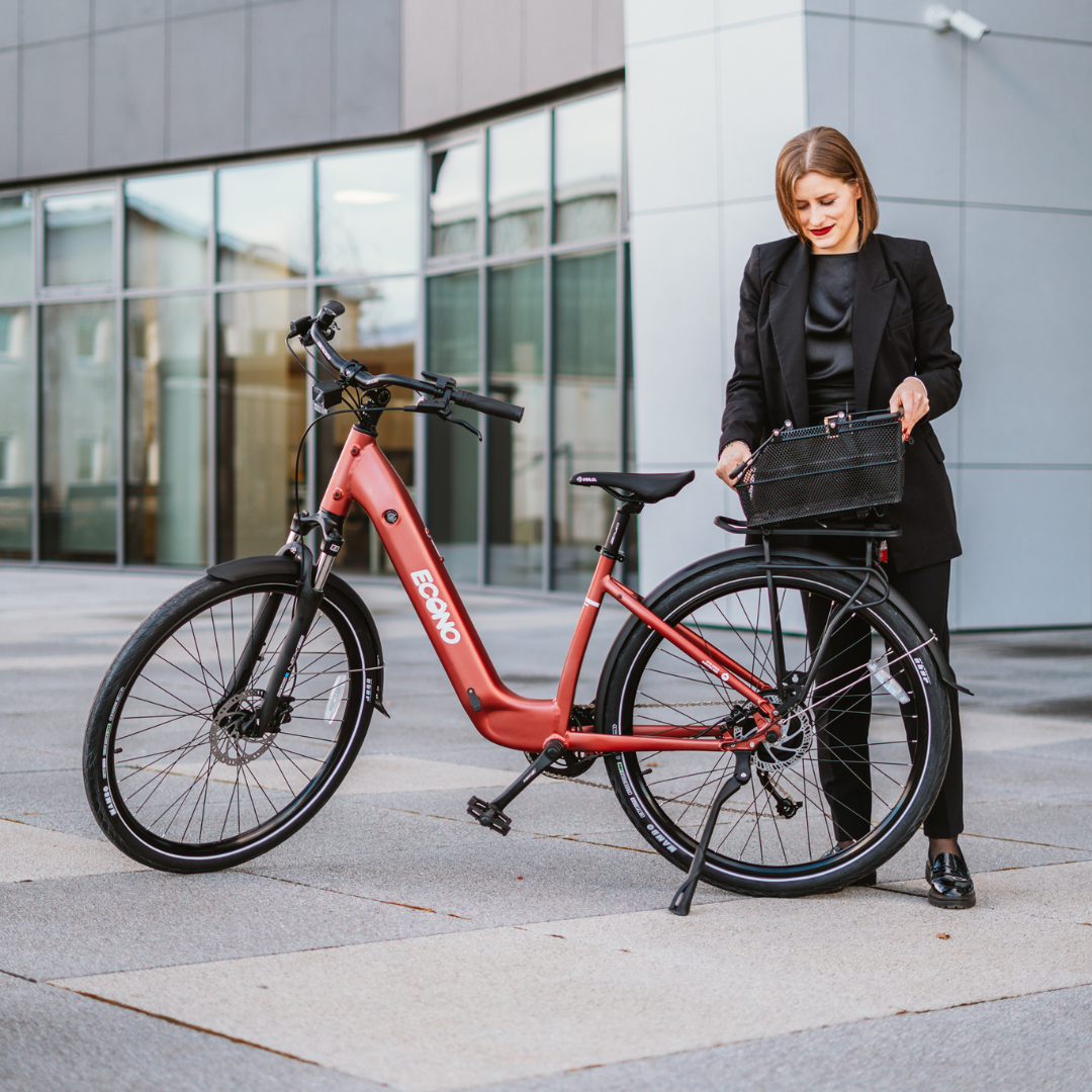 Crveni električni bicikl Econo Apes EER4 s košarom i poslovna žena na otvorenom, bočni pogled