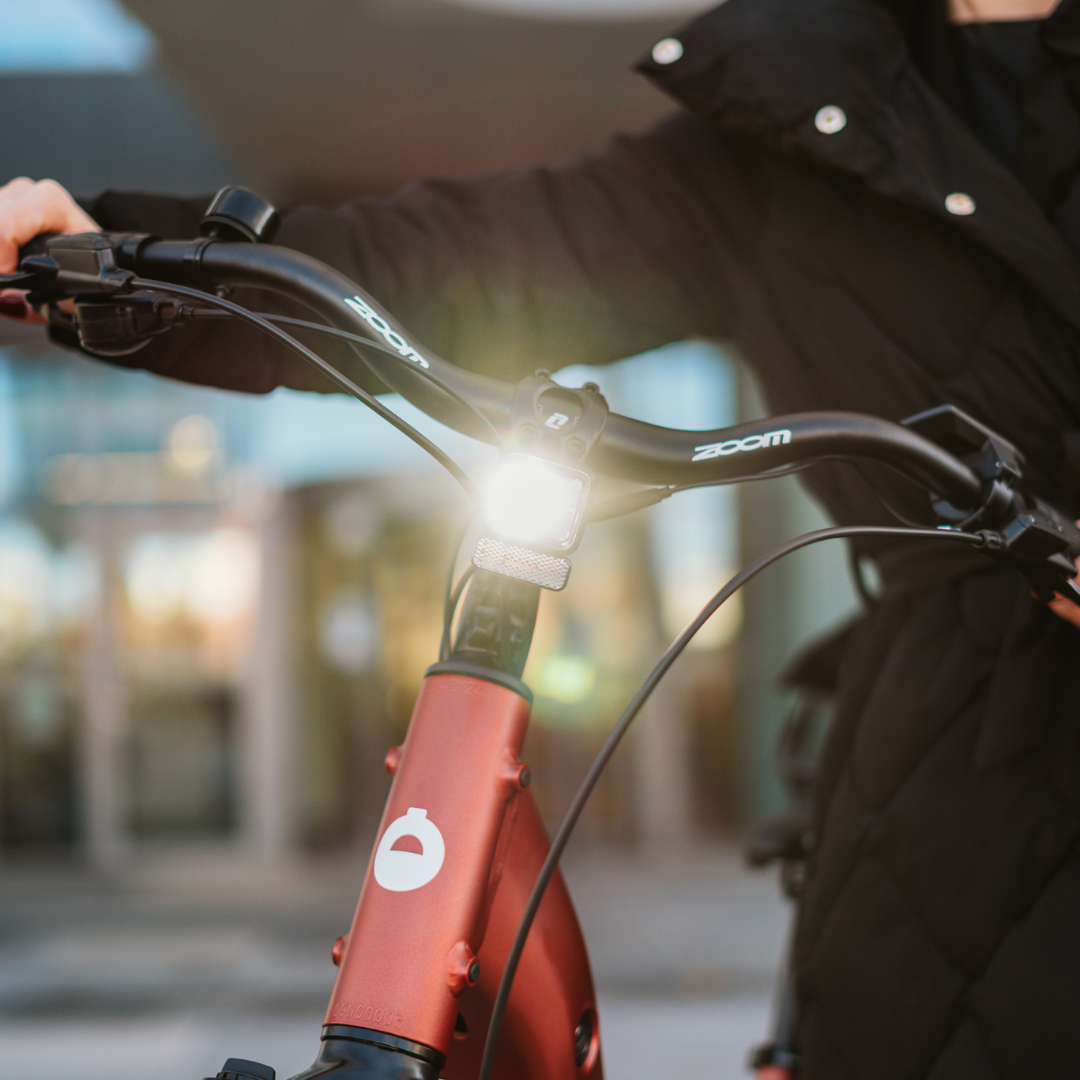 Prednji dio električnog bicikla Econo Apes EER4 s upaljenim bijelim svjetlom i crnim Zoom volanom