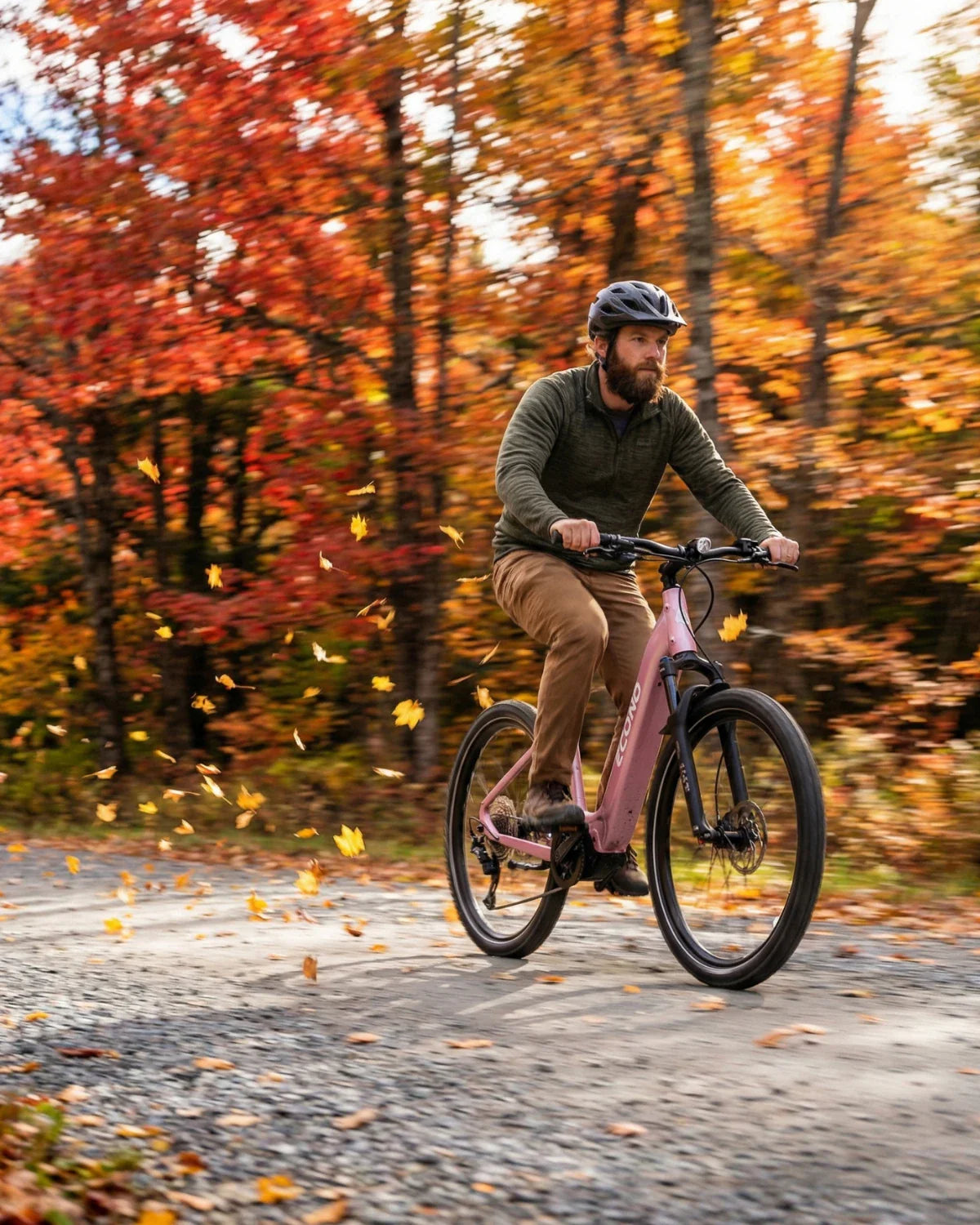 Muškarac vozi ružičasti električni bicikl Econo Gams MTB 29 u jesenjoj šumi s lišćem u pokretu