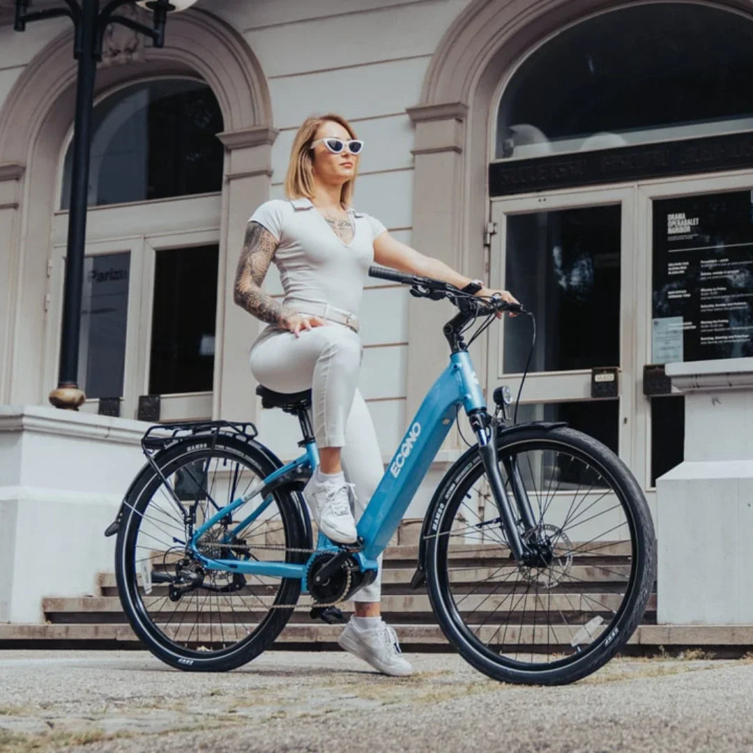 Žena na plavom električnom biciklu Econo Mare City, bočni pogled na gradski e-bicikl ispred zgrade