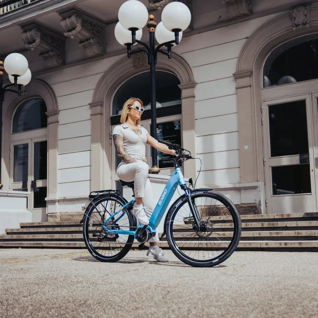 Žena pozira na svijetloplavom električnom biciklu Econo Mare City ispred zgrade