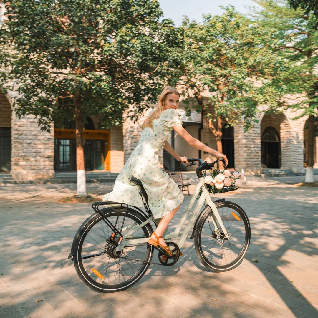 Žena na svijetlozelenom električnom biciklu Fiido City C700 s košarom cvijeća u parku