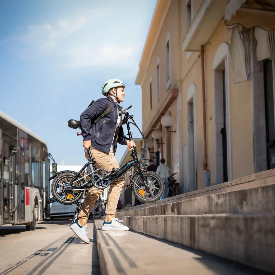 Muškarac nosi crni električni bicikl Fiido D3 Pro Mini uz stepenice u gradskom okruženju