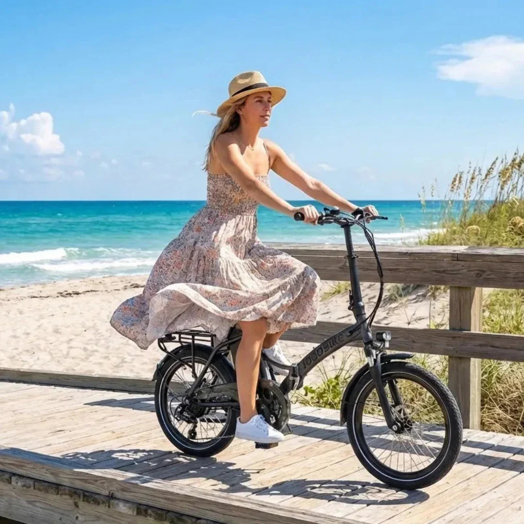 Žena vozi crni električni bicikl Jobobike Sam na drvenoj stazi uz plažu, bočni pogled