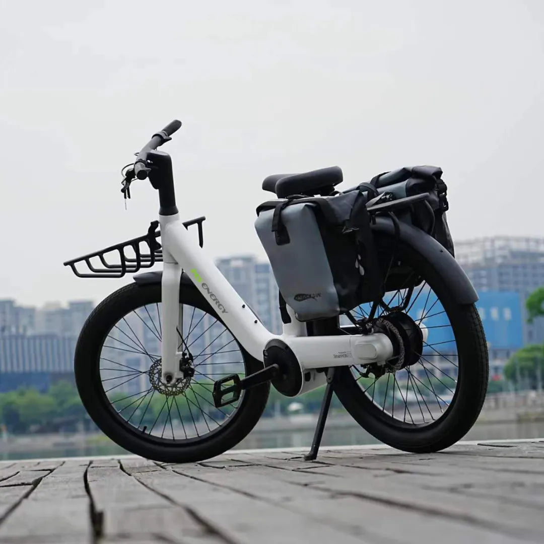 Bijeli električni bicikl MS Energy CityZen c102 s prtljažnikom i torbama na drvenoj podlozi