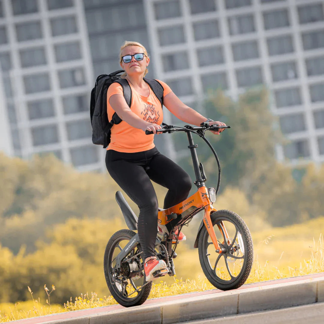 Žena vozi narančasti električni bicikl MS Energy i20 na stazi, pogled s boka
