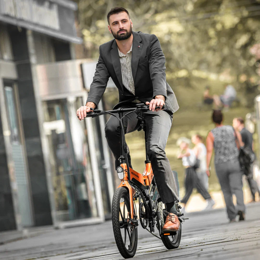 Poslovni čovjek vozi narančasti električni bicikl MS Energy i20 gradskom ulicom, prednji pogled