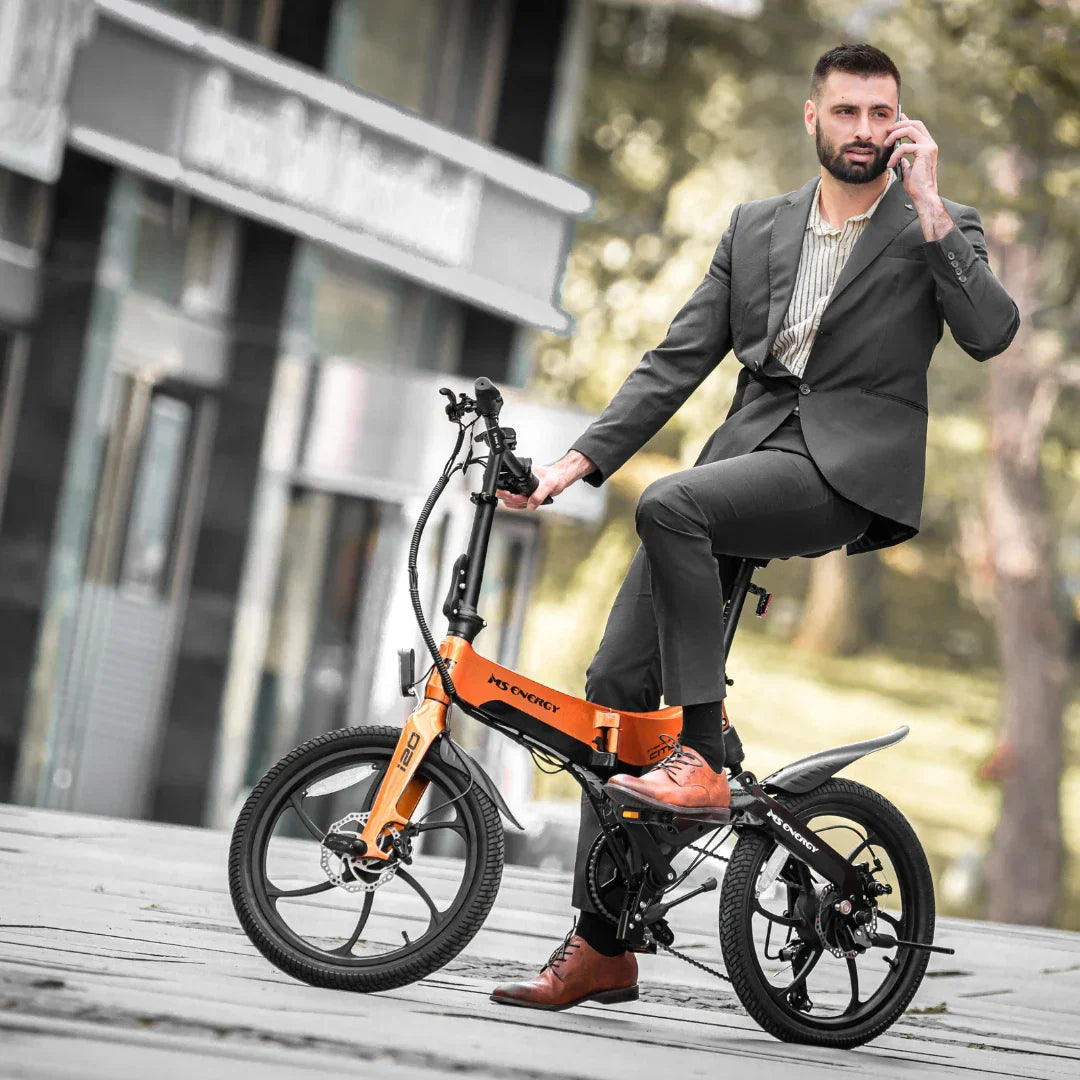 Poslovni čovjek na narančastom električnom biciklu MS Energy i20 u gradskom okruženju