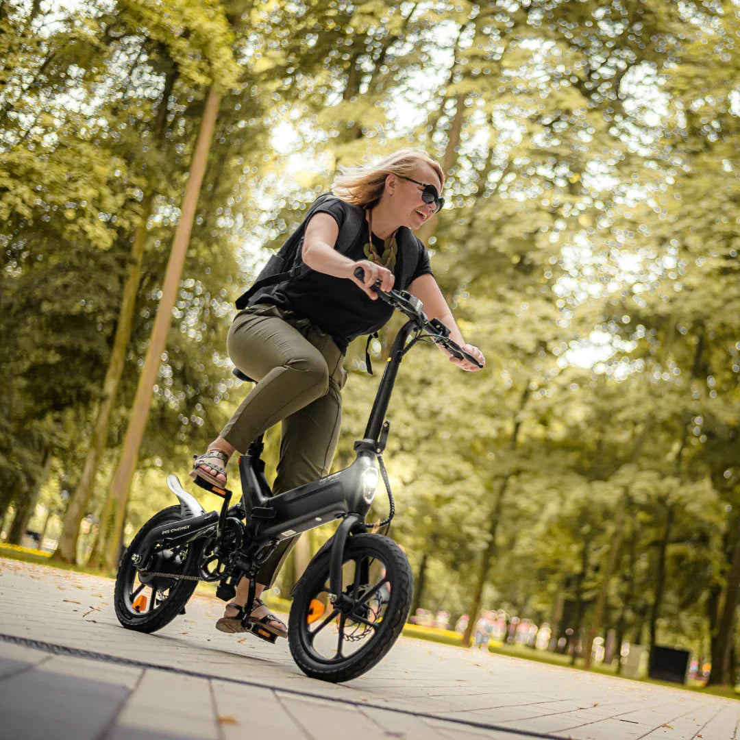 Žena vozi crni električni bicikl MS Energy UrbanFold i6 u parku, pogled iz donjeg kuta