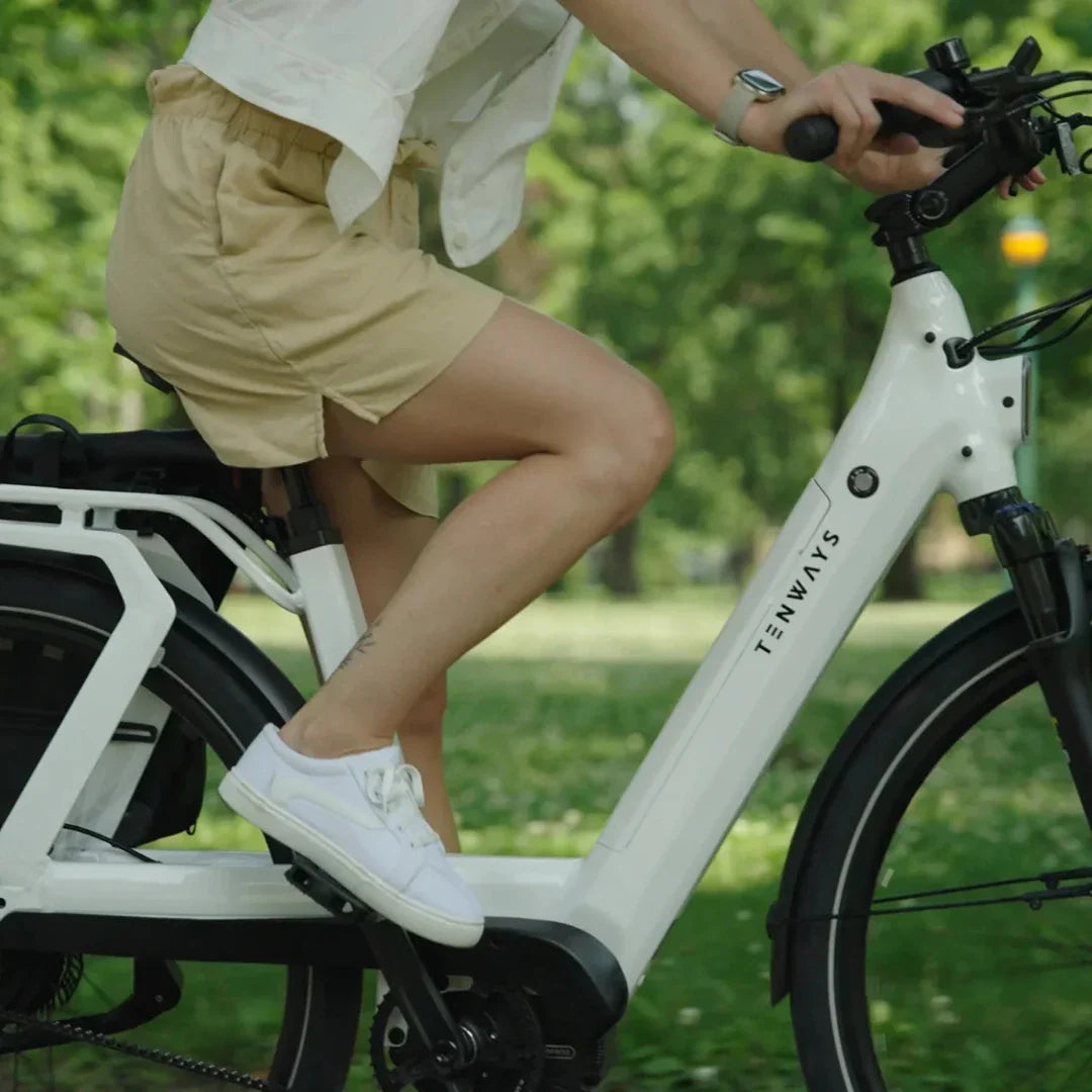 Bijeli električni bicikl Tenways AGO T, detalj vozačice u vožnji kroz park, bočni pogled