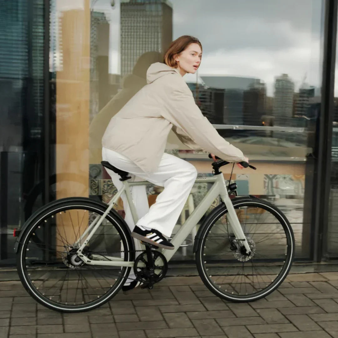 Žena vozi sivi električni bicikl Tenways CGO600 Pro Plus pored staklene zgrade u gradu
