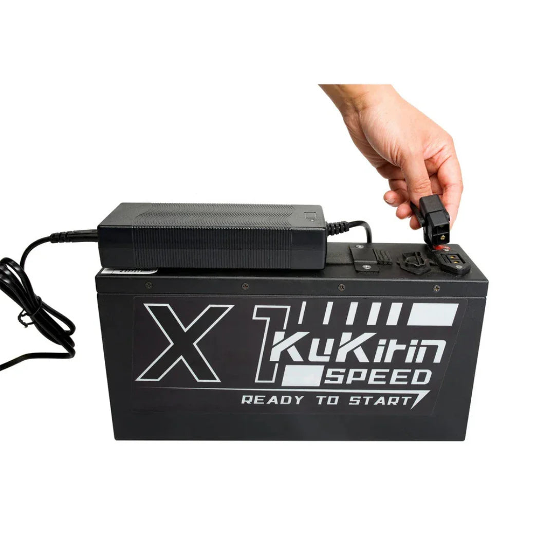 Crna litijska baterija za električni kros motor KuKirin X1 s punjačem u ruci pri spajanju