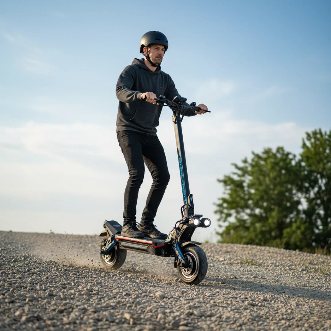 Muškarac vozi crni električni romobil Dualtron Storm Limited po šljunčanoj cesti