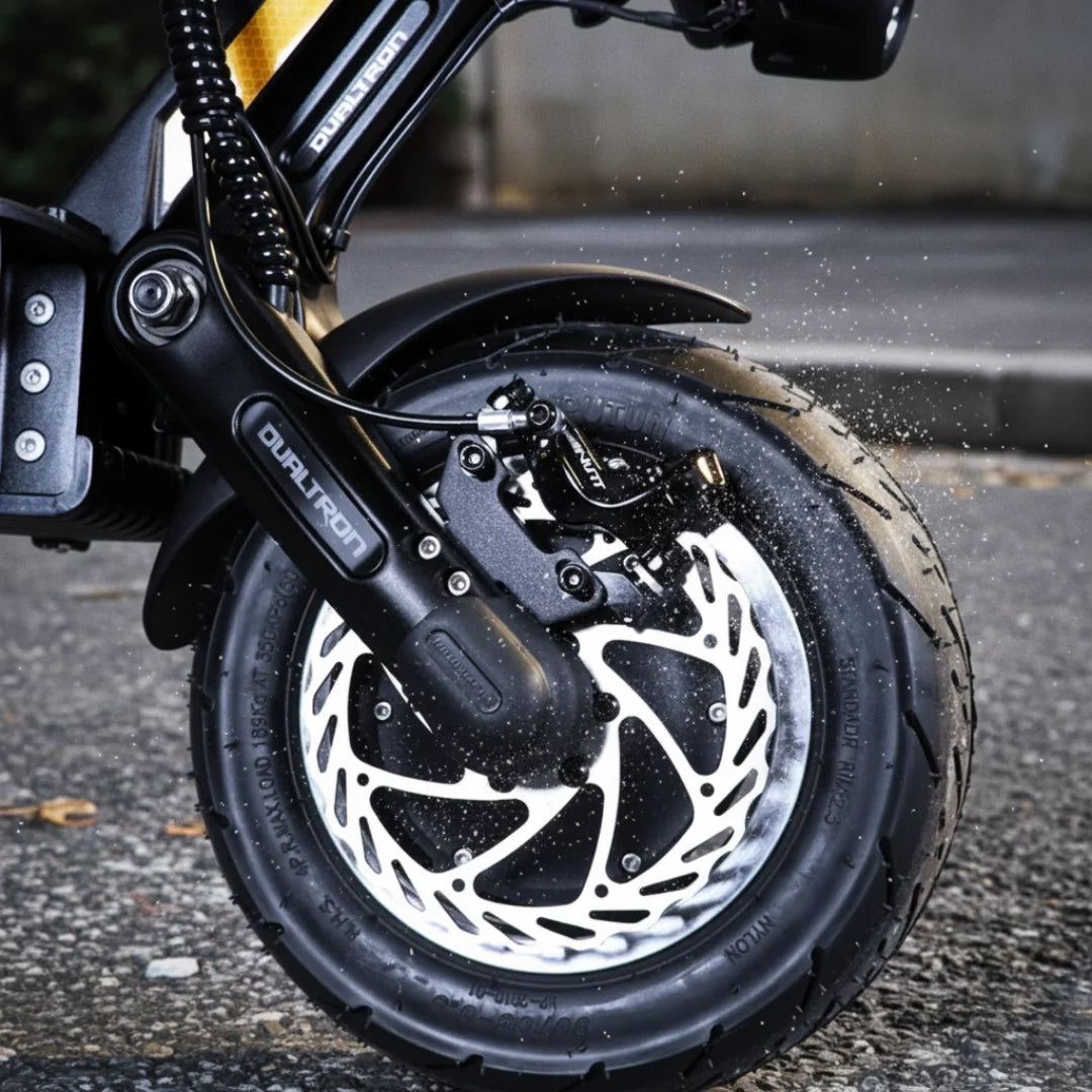 Krupni plan crnog kotača i disk kočnice električnog romobila Dualtron Thunder 3 na cesti