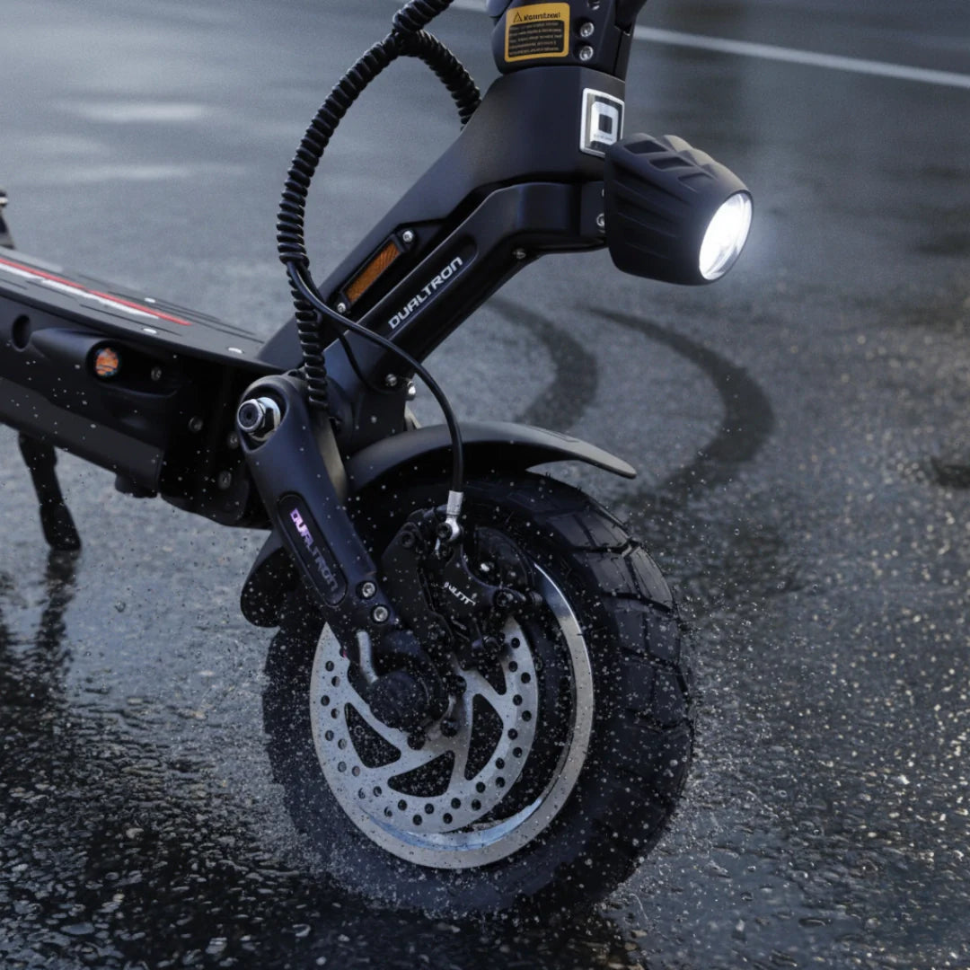 Krupni plan prednjeg kotača crnog električnog romobila Dualtron Victor Limited na mokroj cesti