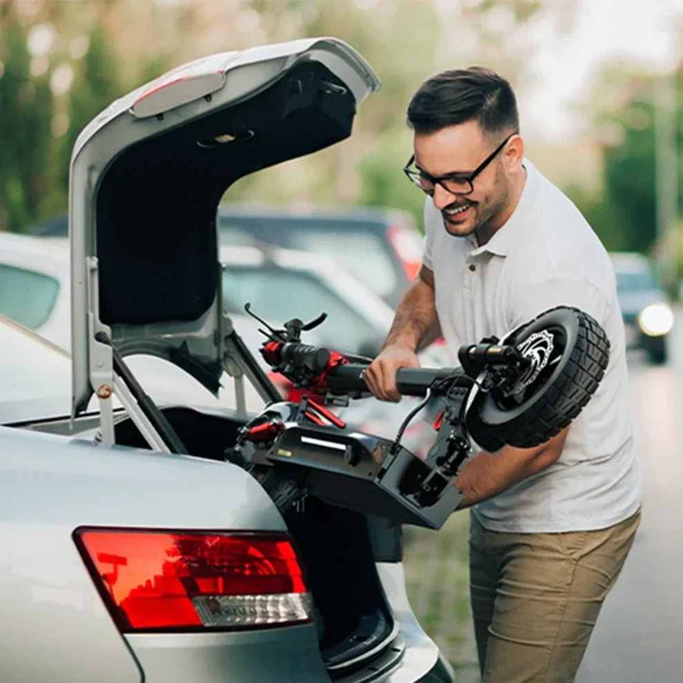 Muškarac sprema crni električni romobil Engwe Y600s u prtljažnik automobila