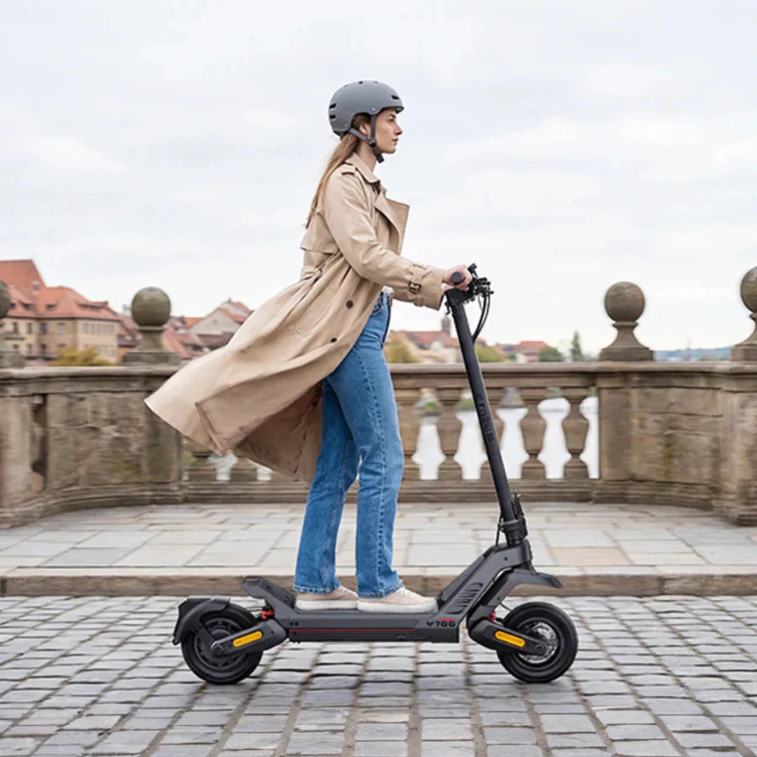 Žena s kacigom vozi crni električni romobil Engwe Y700 na popločenoj stazi, profilni pogled