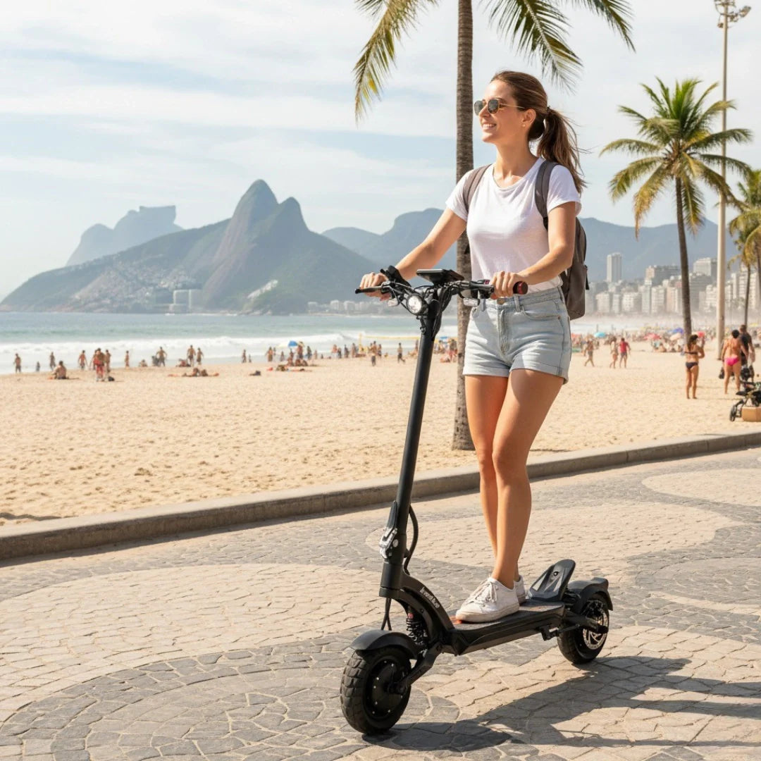 Djevojka vozi crni električni romobil Kaabo Mantis X Plus na šetnici uz plažu, pogled sa strane