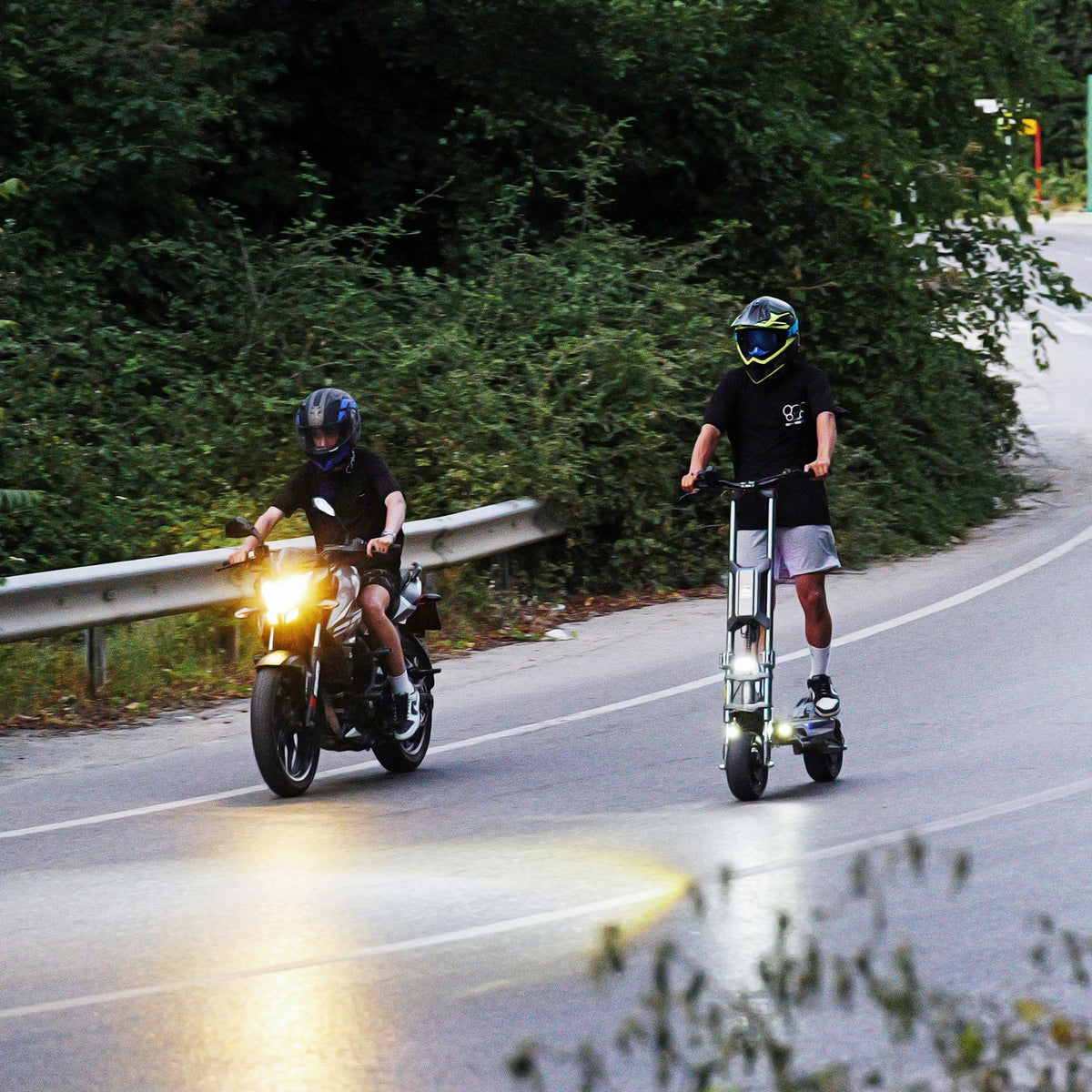 Električni romobil Langfeite H1 i motocikl u vožnji cestom uz prirodu