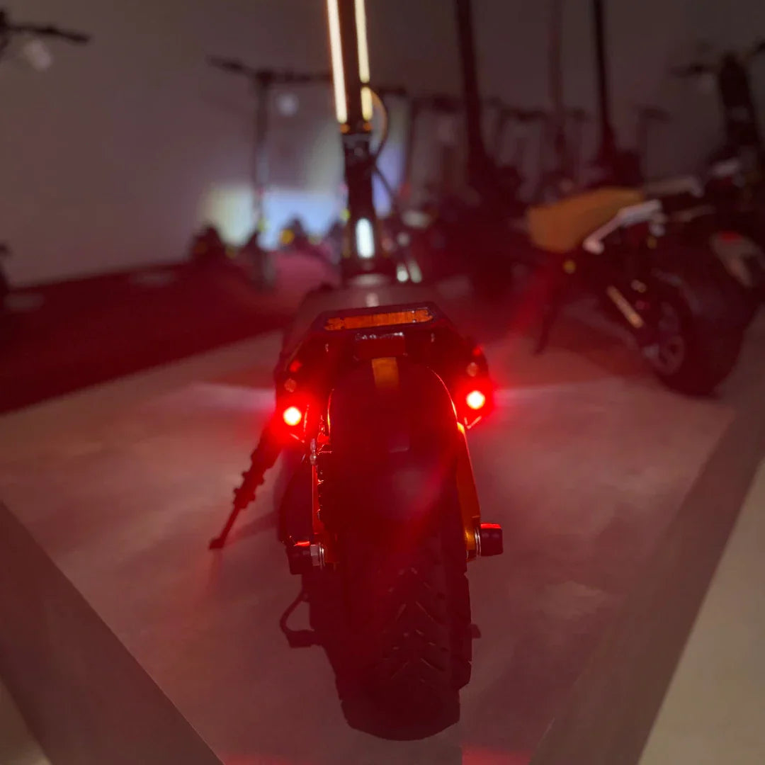 Stražnji pogled na električni romobil MS Energy Flare X Pro s upaljenim crvenim svjetlima u mraku