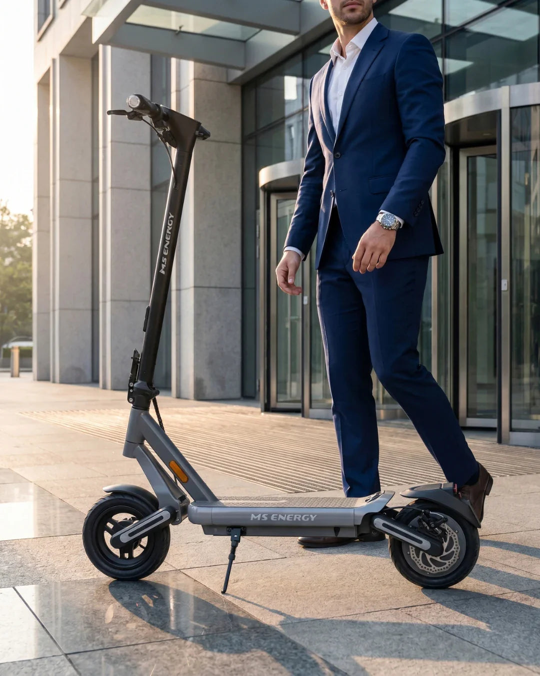 Električni romobil MS Energy Mentor 500 u sivoj boji s poslovnim čovjekom ispred zgrade