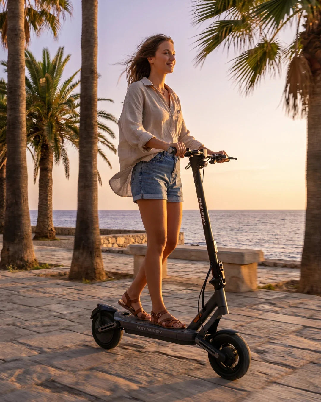 Djevojka vozi crni električni romobil MS Energy Mentor 500 uz obalu pored palmi