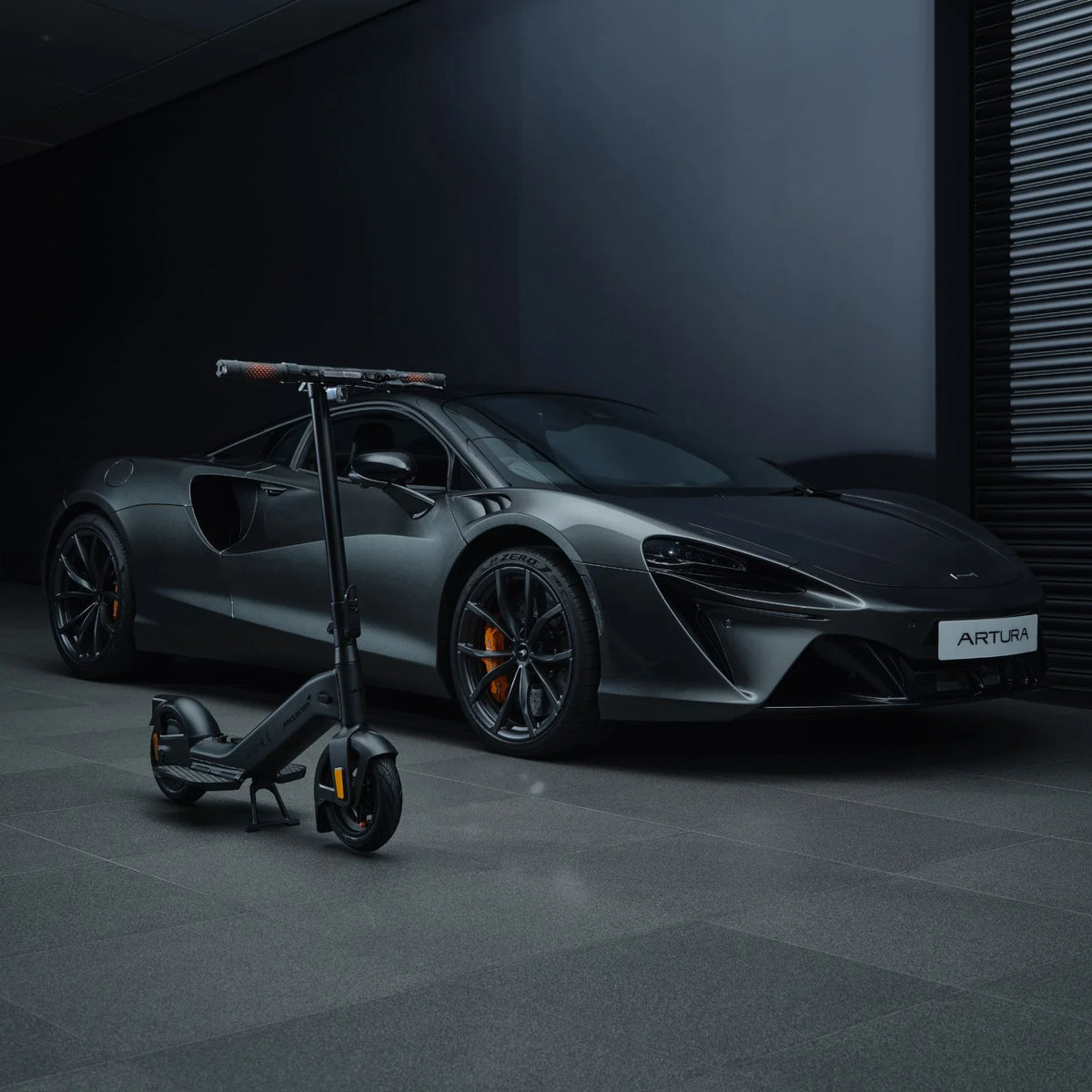 Crni električni romobil Pure Advance McLaren Edition ispred McLaren Artura automobila u garaži