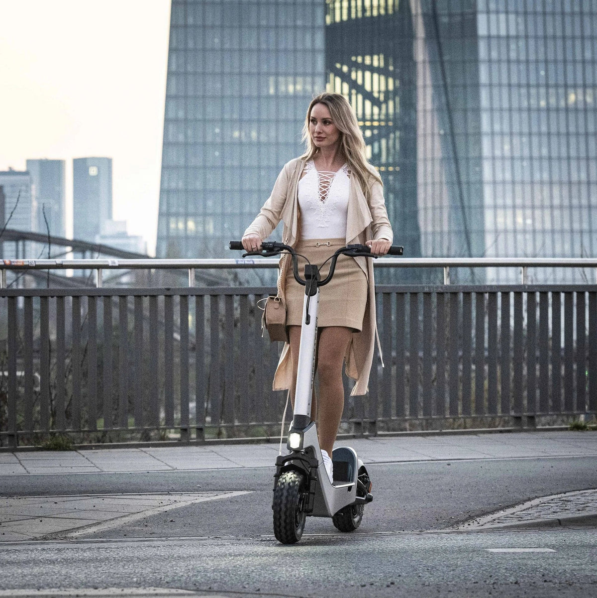 Žena vozi bijeli električni romobil Streetbooster Castor na gradskoj ulici