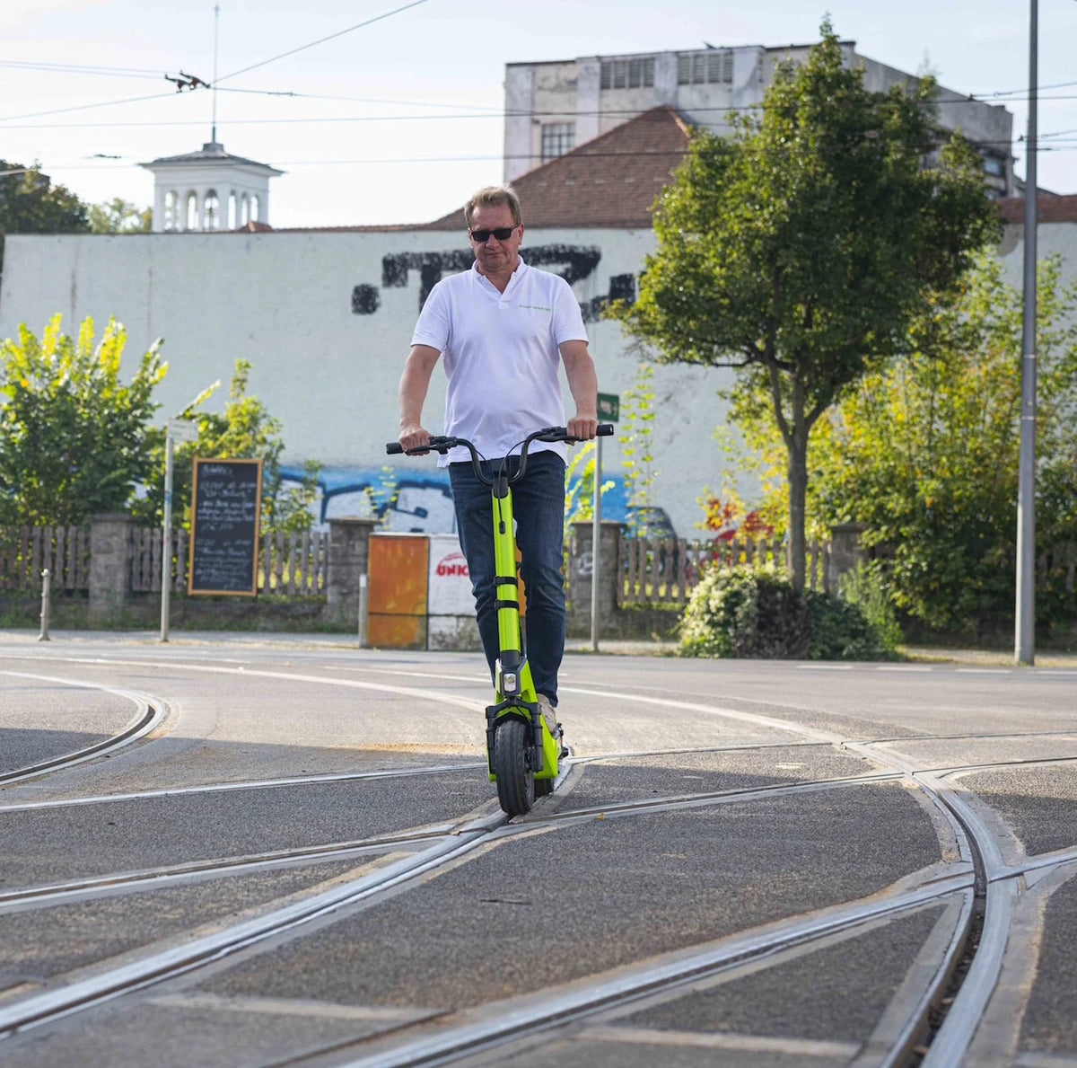 Muškarac vozi zeleni električni romobil Streetbooster Castor po gradskim tračnicama