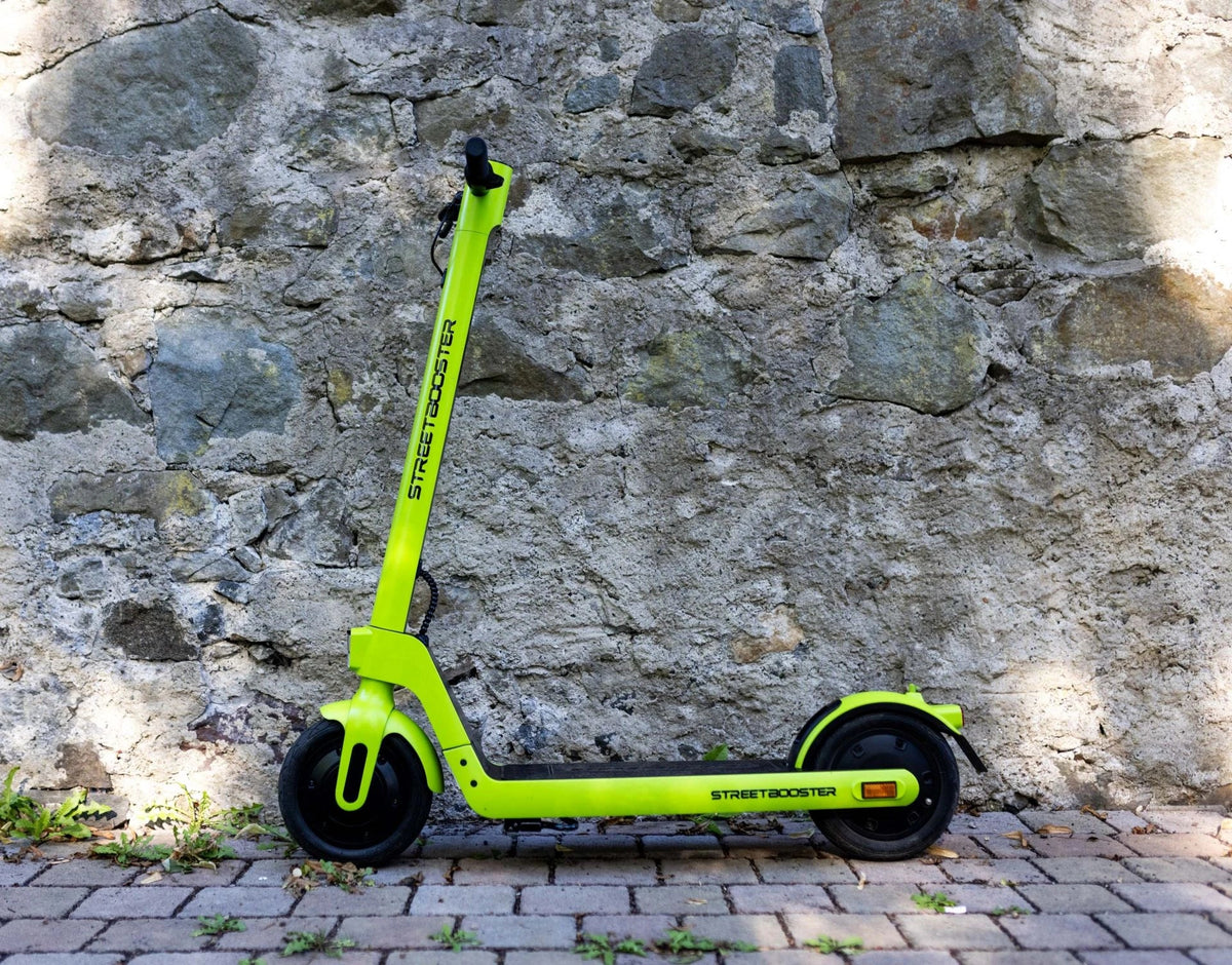 Zeleni električni romobil Streetbooster Sirius parkiran uz kameni zid