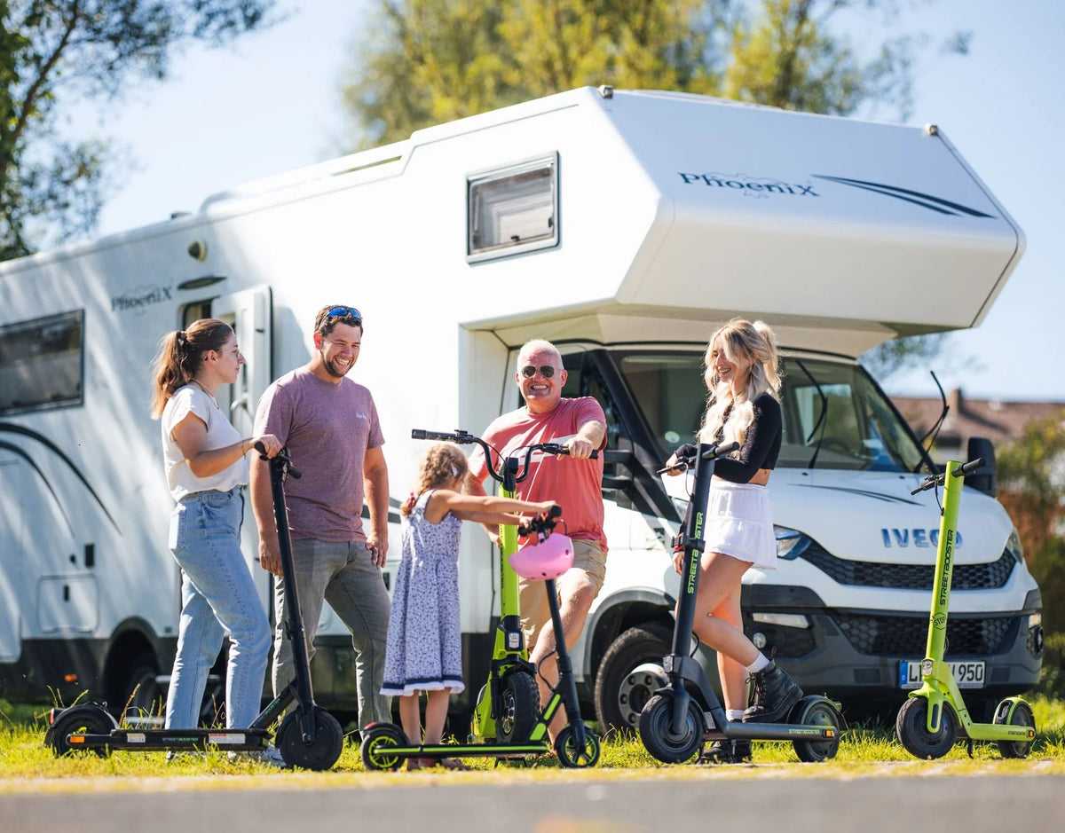 Obitelj s električnim romobilima Streetbooster Sirius pored kampera na otvorenom