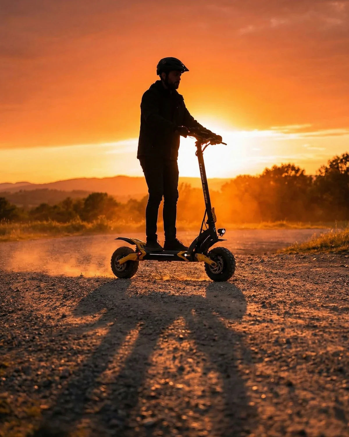 Muškarac vozi električni romobil Teverun Blade Mini Ultra na makadamu pri zalasku sunca bočni pogled