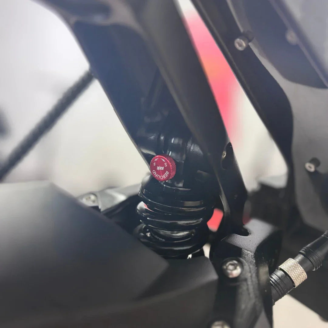 Detalj stražnjeg crnog amortizera s crvenim gumbom za podešavanje na romobilu Teverun Fighter Mini