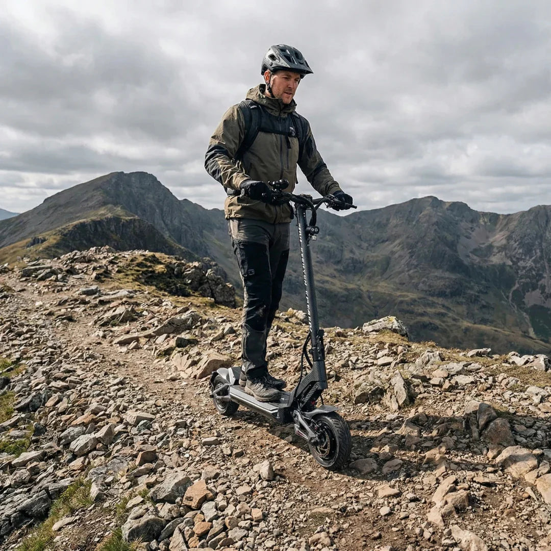 Muškarac vozi crni električni romobil Teverun Fighter Mini Pro 2026 na stjenovitom planinskom putu