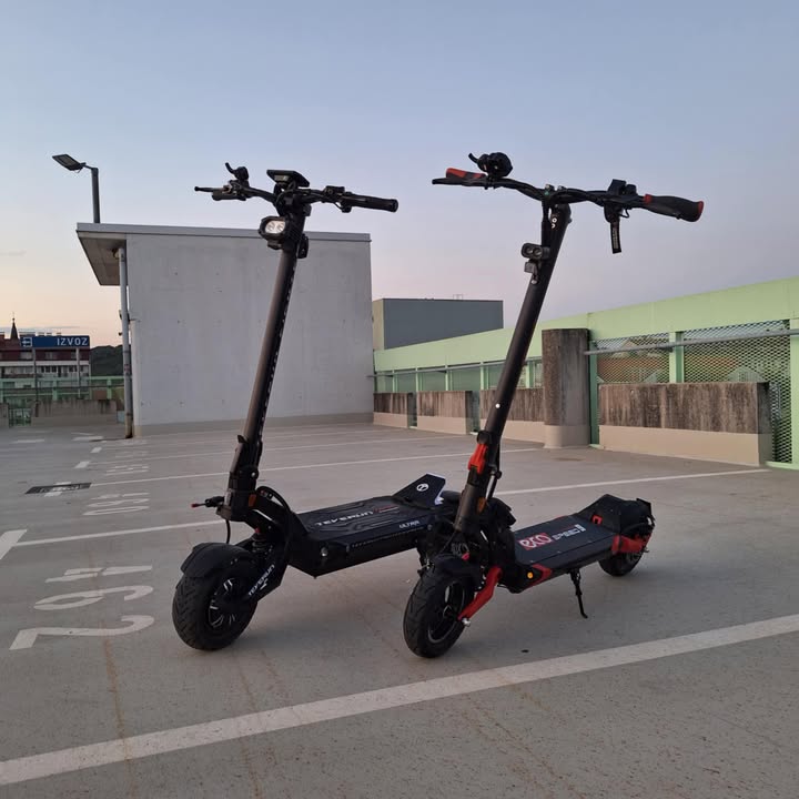 Crni električni romobili Teverun Fighter Supreme i Ultra parkirani na otvorenom, bočni pogled