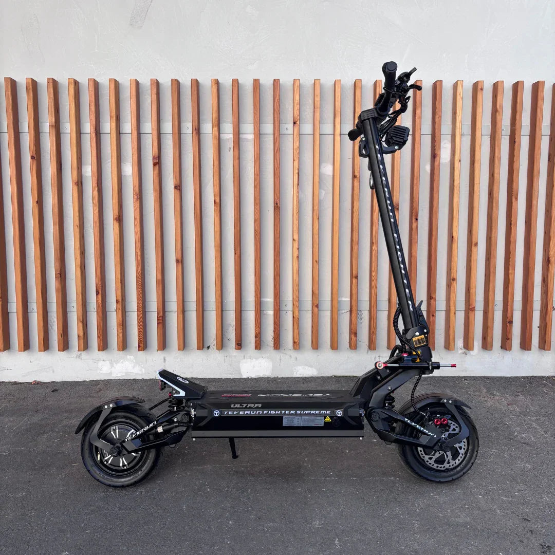 Crni električni romobil Teverun Fighter Supreme 7260 Ultra, bočni prikaz na drvenoj podlozi