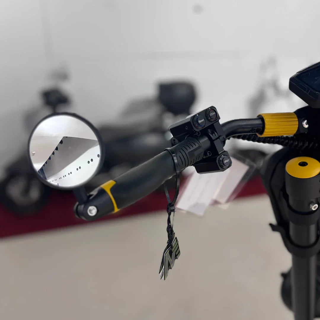 Krupni plan upravljača električnog romobila Vsett 11+ s retrovizorom i tipkama crno-žute boje